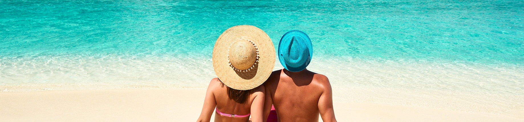 Male and female sat at a beach relaxing in the sun