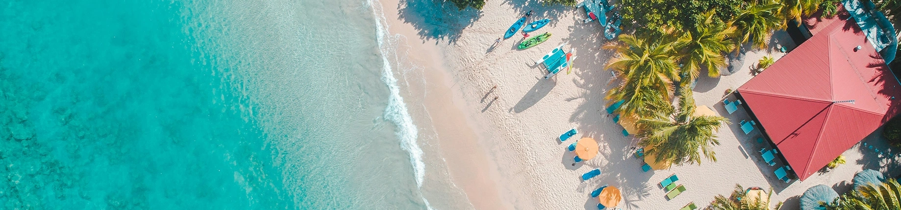 image of a beach from the sky with bright blue water and white sand.